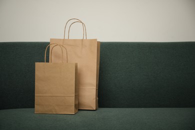 Photo of Paper bags on sofa at home. Space for text