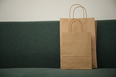 Photo of Paper bags on sofa at home. Space for text