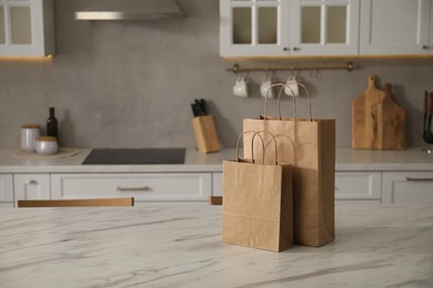 Photo of Paper bags on white marble table in kitchen. Space for text