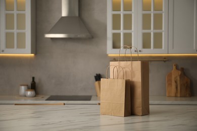 Photo of Paper bags on white marble table in kitchen. Space for text