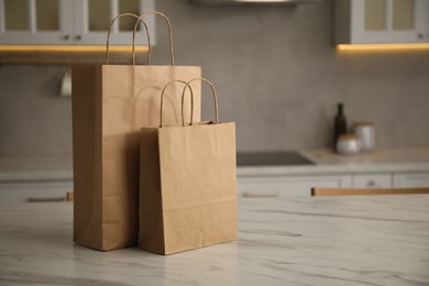 Photo of Paper bags on white marble table in kitchen. Space for text