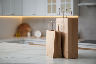 Photo of Paper bags on white marble table in kitchen. Space for text