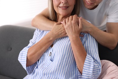Photo of Son hugging his mother indoors, closeup. Family bonding