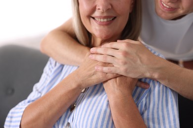 Photo of Son hugging his mother indoors, closeup. Family bonding