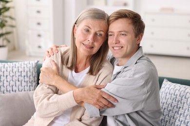 Photo of Happy son and his mother hugging on sofa at home