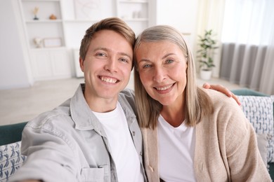 Photo of Happy son and his mother taking selfie at home