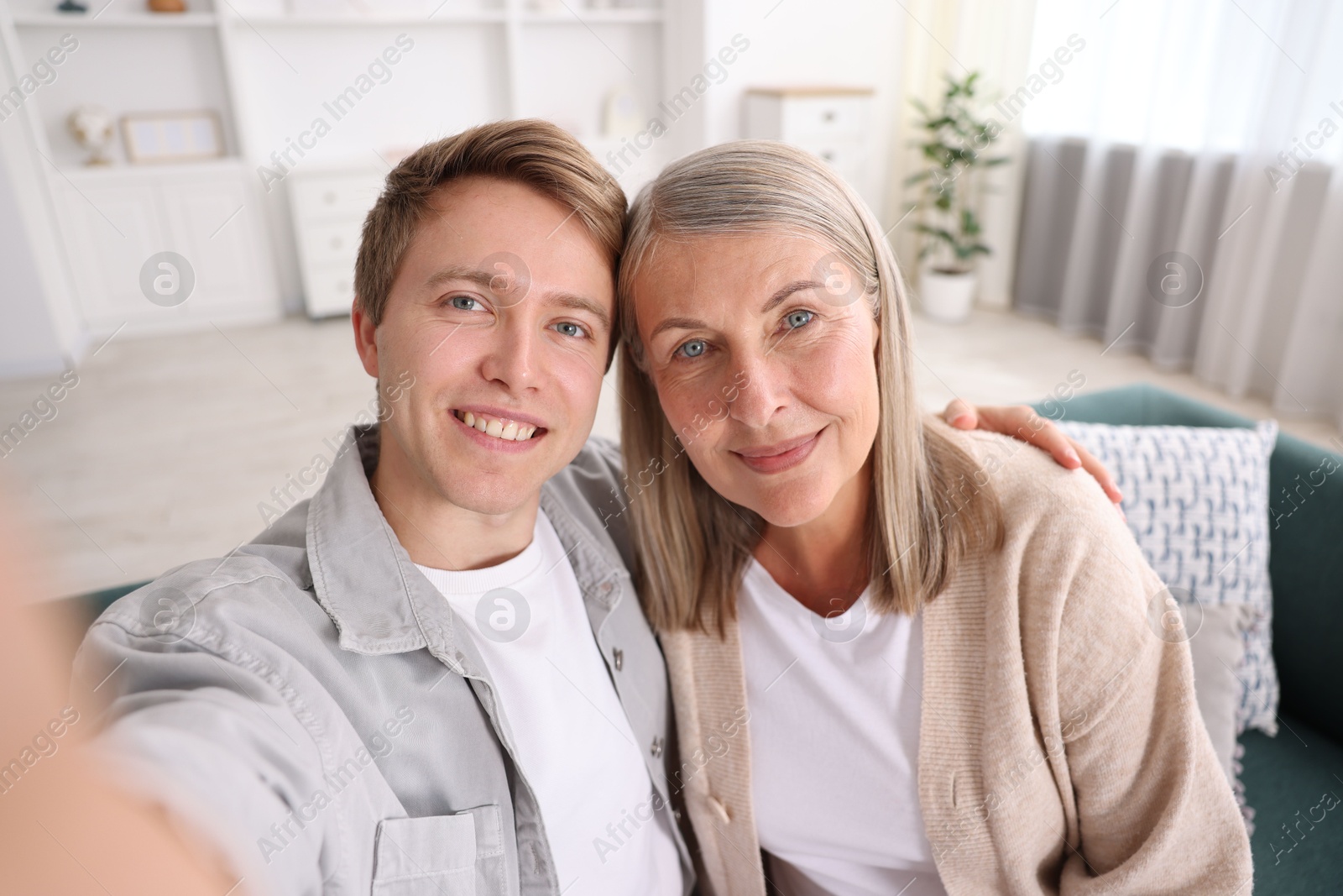 Photo of Happy son and his mother taking selfie at home