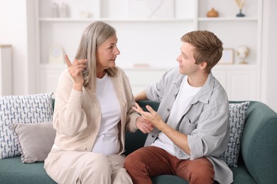 Photo of Happy son and his mother talking on sofa at home