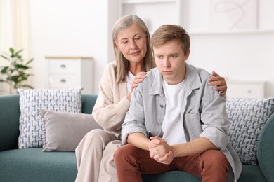 Photo of Mother supporting her son on sofa at home
