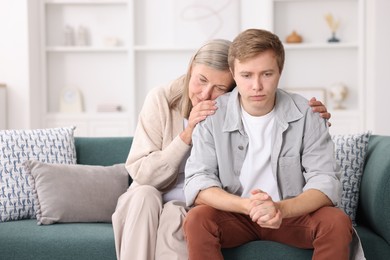 Photo of Mother supporting her son on sofa at home