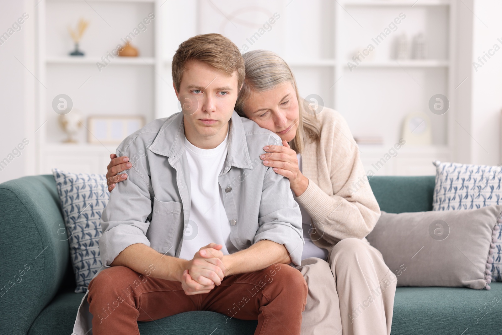 Photo of Mother supporting her son on sofa at home