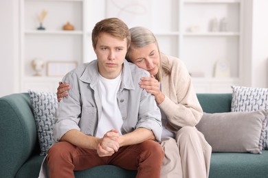 Photo of Mother supporting her son on sofa at home