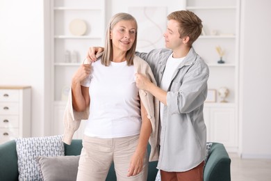 Photo of Son taking care of his happy mother at home. Family bonding