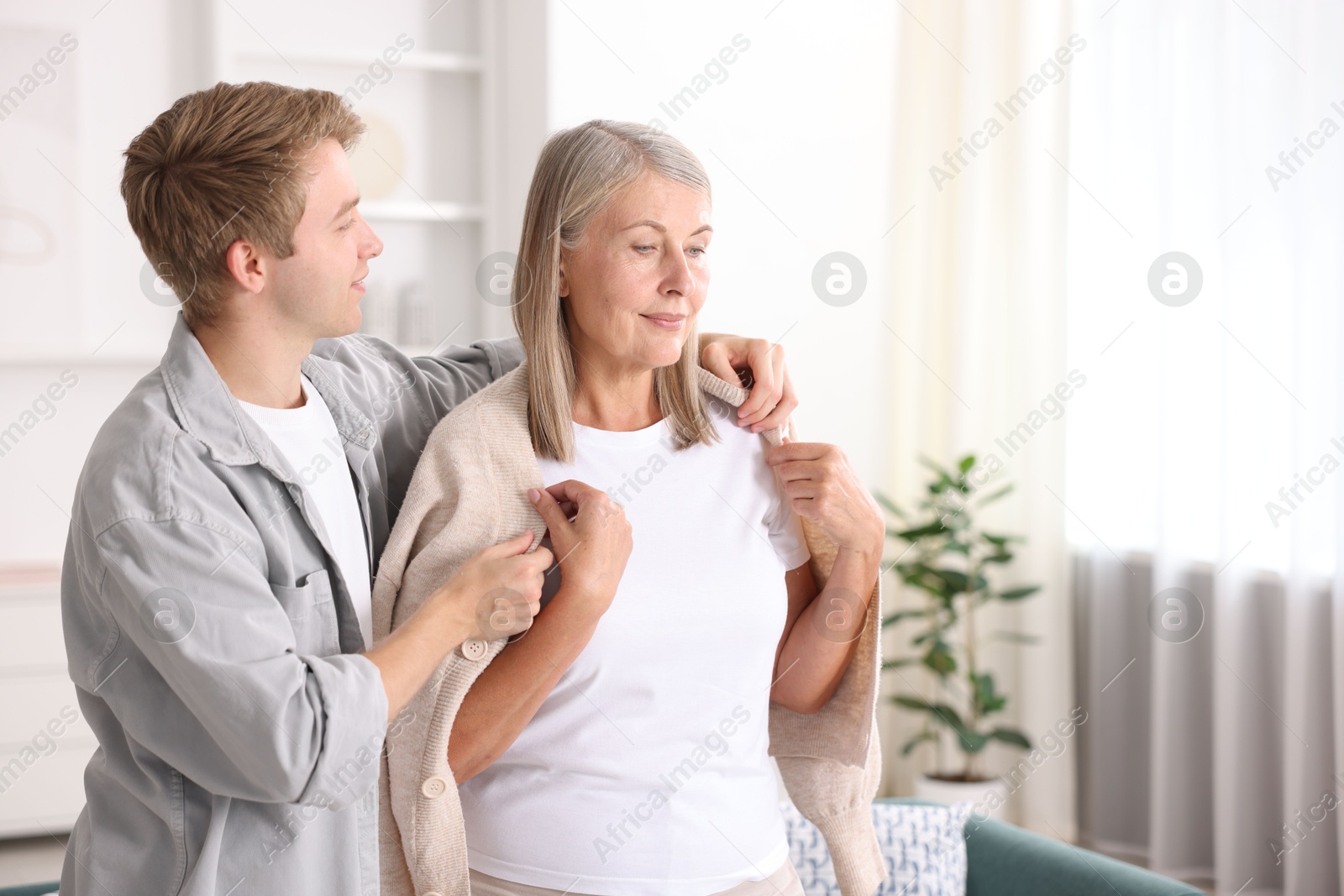 Photo of Son taking care of his mother at home. Space for text