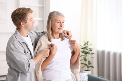 Photo of Son taking care of his mother at home. Space for text