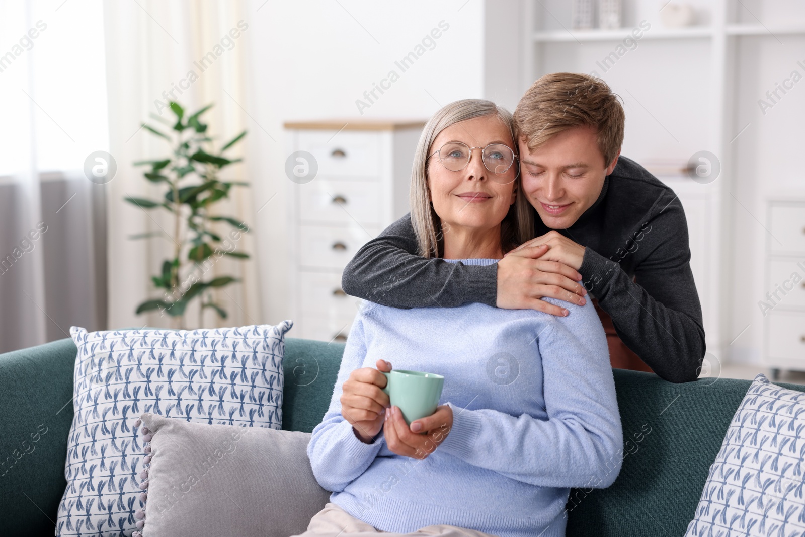 Photo of Son hugging his mother with cup at home