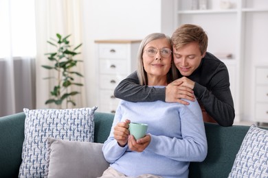 Photo of Son hugging his mother with cup at home