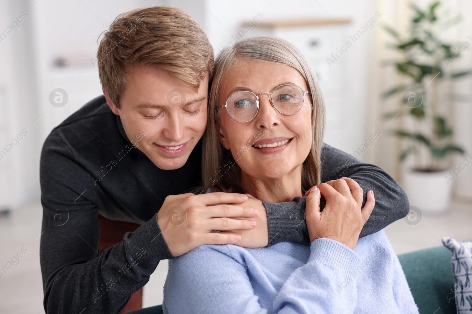 Photo of Smiling son hugging his mother at home. Family bonding