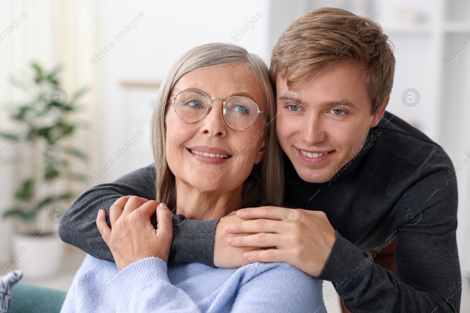 Photo of Smiling son hugging his mother at home. Family bonding