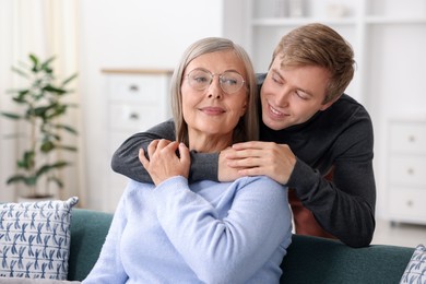 Photo of Smiling son hugging his mother at home. Family bonding