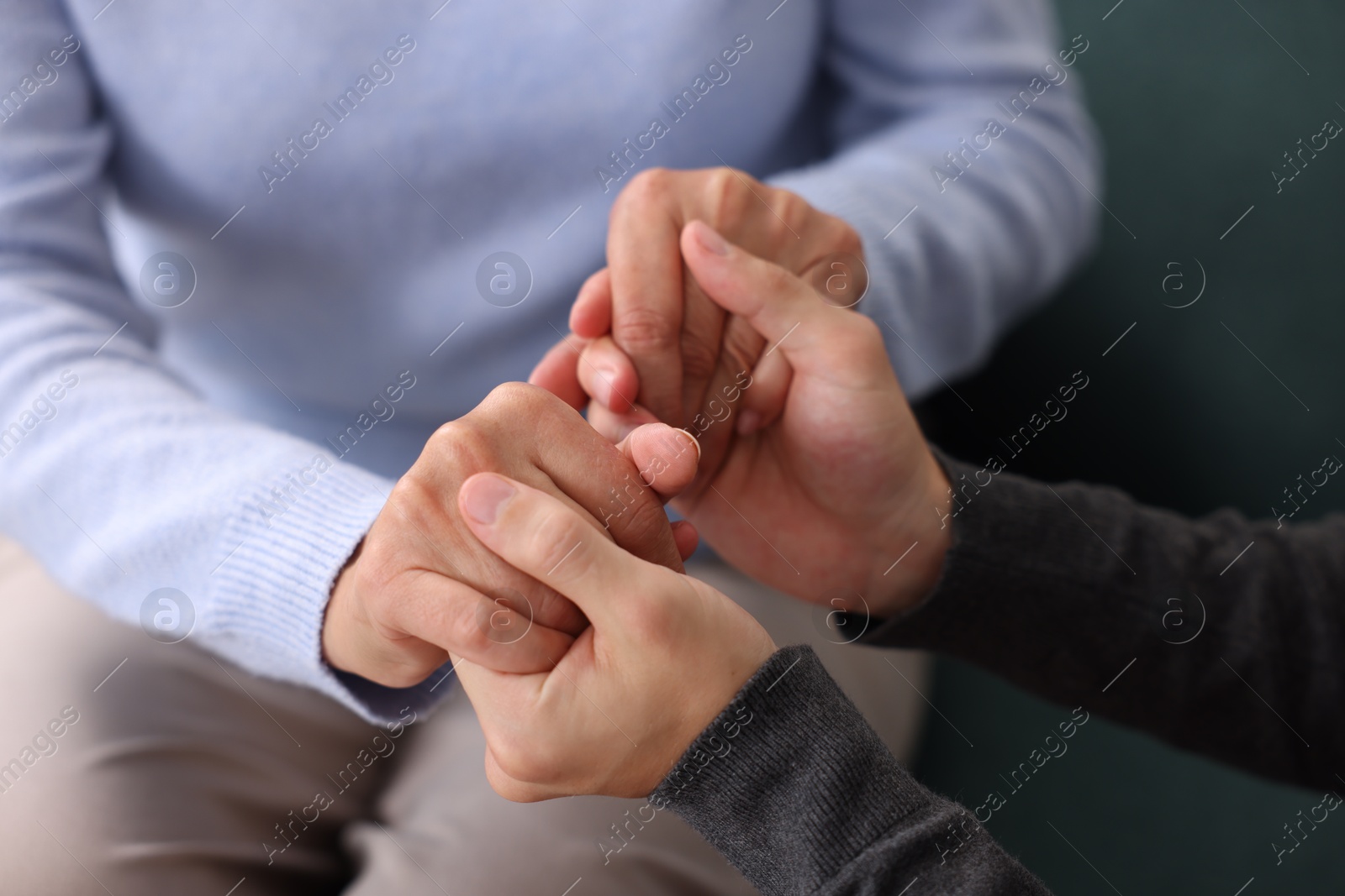 Photo of Son and his mother holding hands indoors, closeup