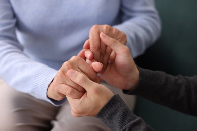 Photo of Son and his mother holding hands indoors, closeup