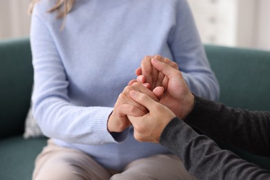 Photo of Son and his mother holding hands indoors, closeup