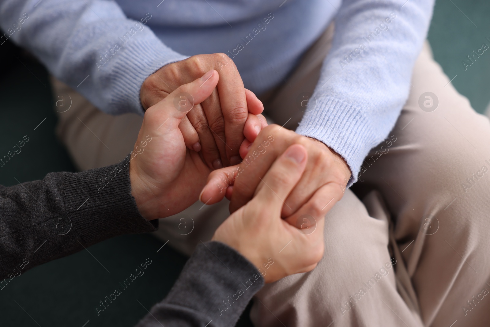 Photo of Son and his mother holding hands indoors, closeup