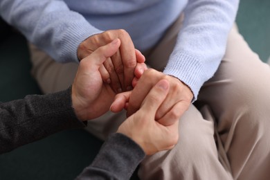 Photo of Son and his mother holding hands indoors, closeup