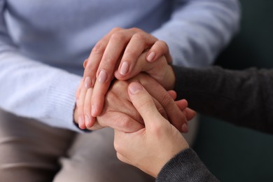 Photo of Son and his mother holding hands indoors, closeup