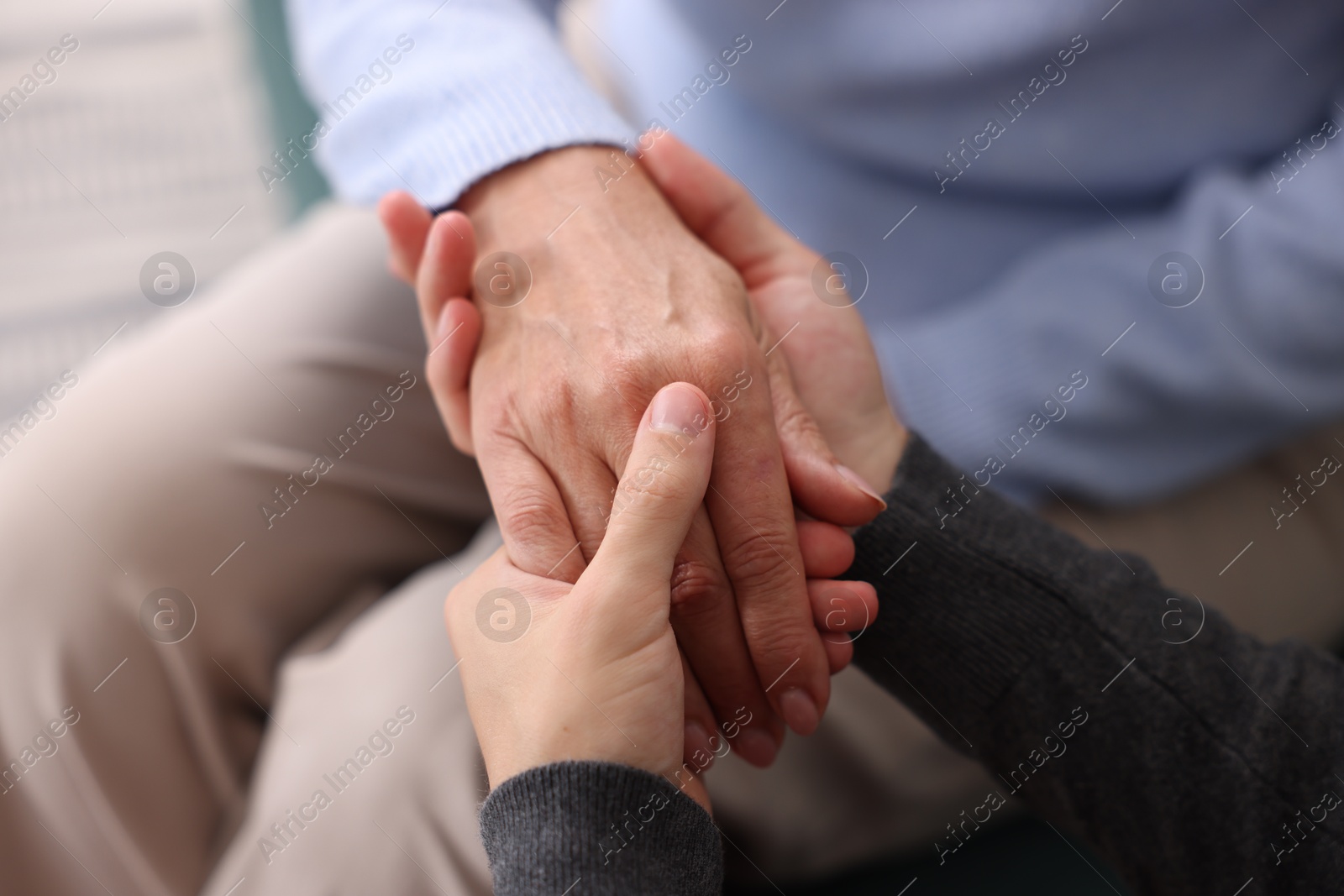 Photo of Son and his mother holding hands indoors, closeup