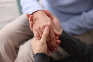 Photo of Son and his mother holding hands indoors, closeup