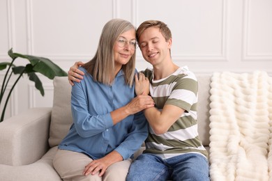 Photo of Happy son and his mother spending time together on sofa at home