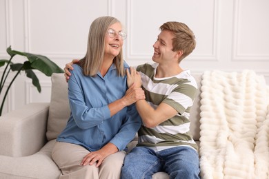 Photo of Happy son and his mother spending time together on sofa at home