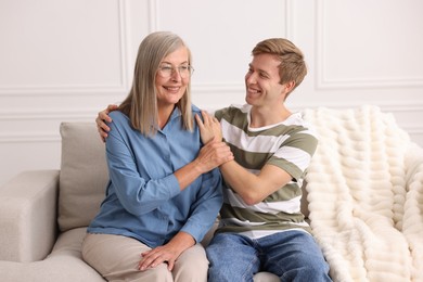 Photo of Happy son and his mother spending time together on sofa at home