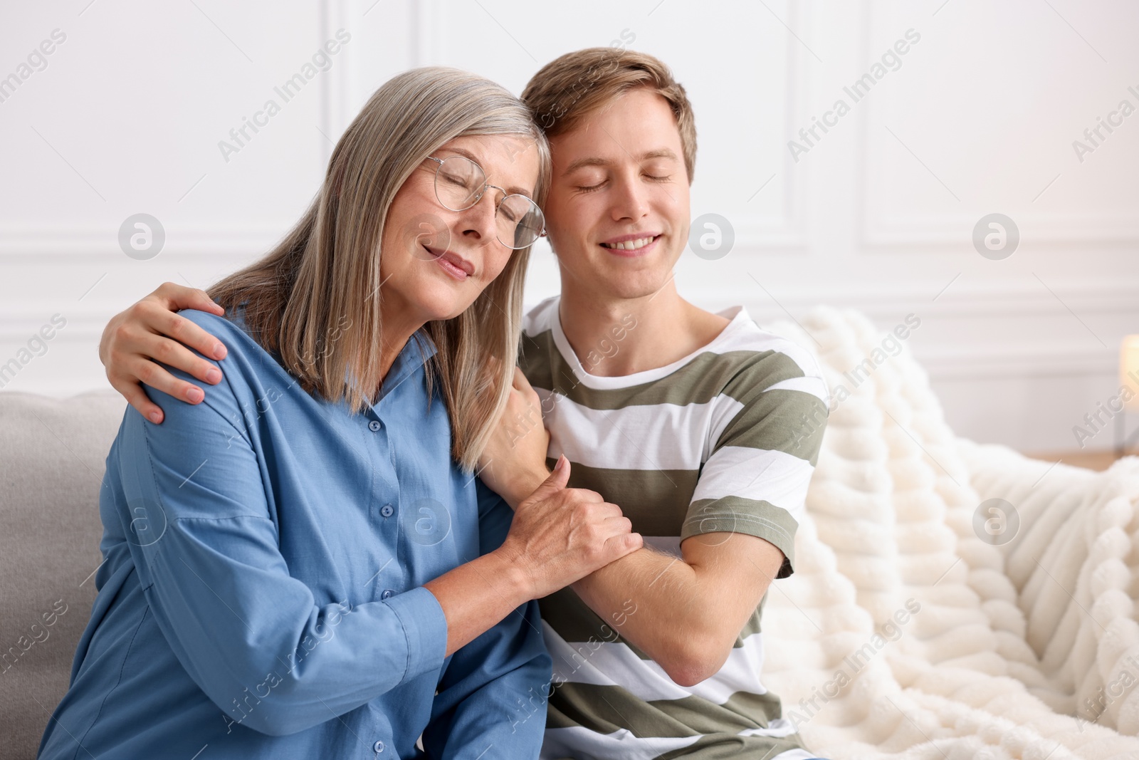 Photo of Happy son and his mother spending time together on sofa at home
