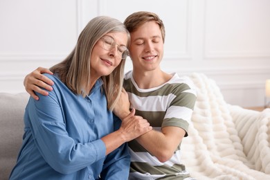 Photo of Happy son and his mother spending time together on sofa at home