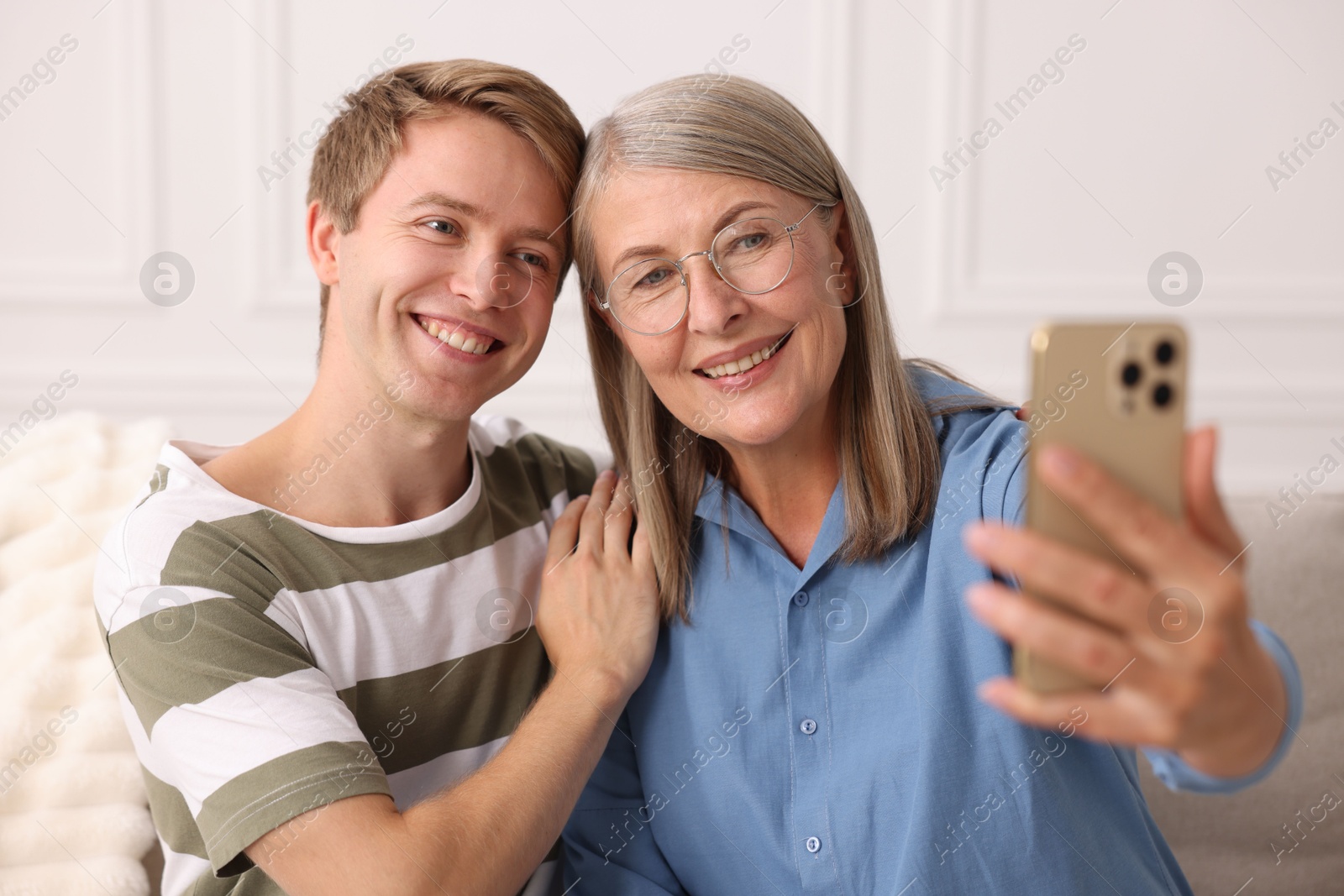 Photo of Happy son and his mother taking selfie at home