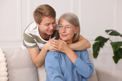 Photo of Smiling son hugging his mother at home. Family bonding