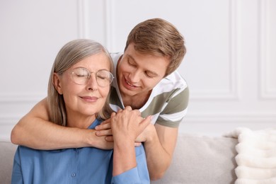 Photo of Smiling son hugging his mother at home. Space for text