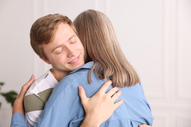 Photo of Smiling son hugging his mother at home