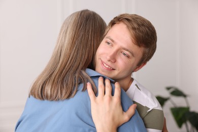 Photo of Smiling son hugging his mother at home
