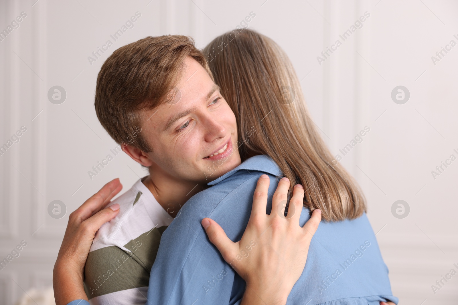 Photo of Smiling son hugging his mother at home