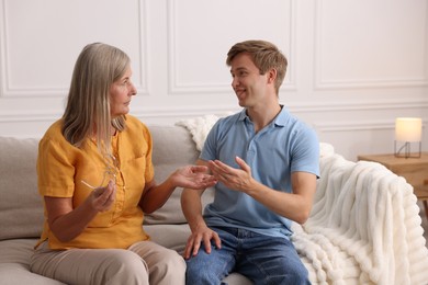 Photo of Happy son and his mother talking on sofa at home