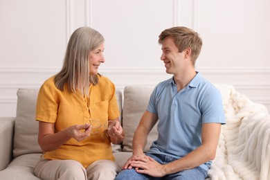Photo of Happy son and his mother talking on sofa at home
