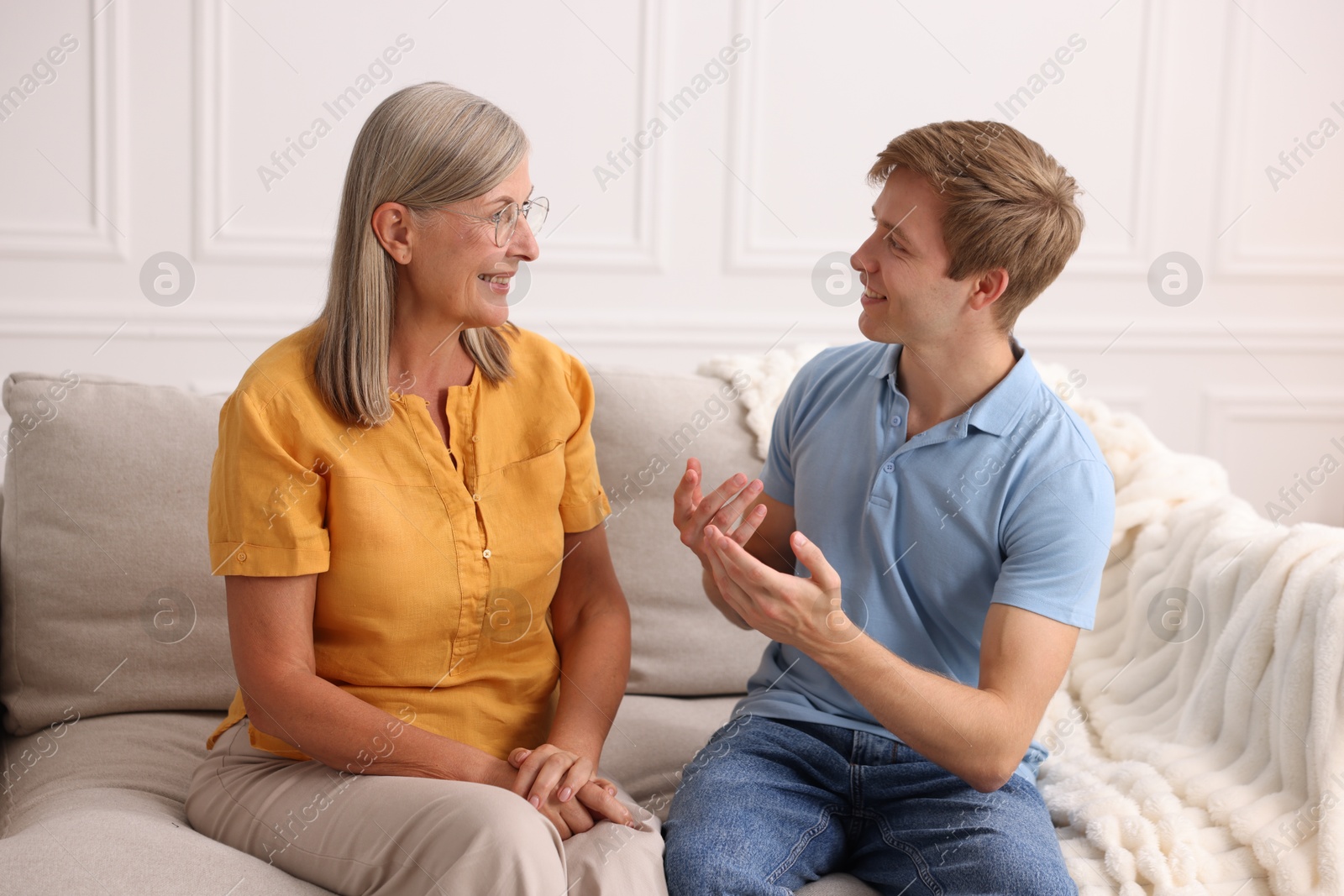 Photo of Happy son and his mother talking on sofa at home