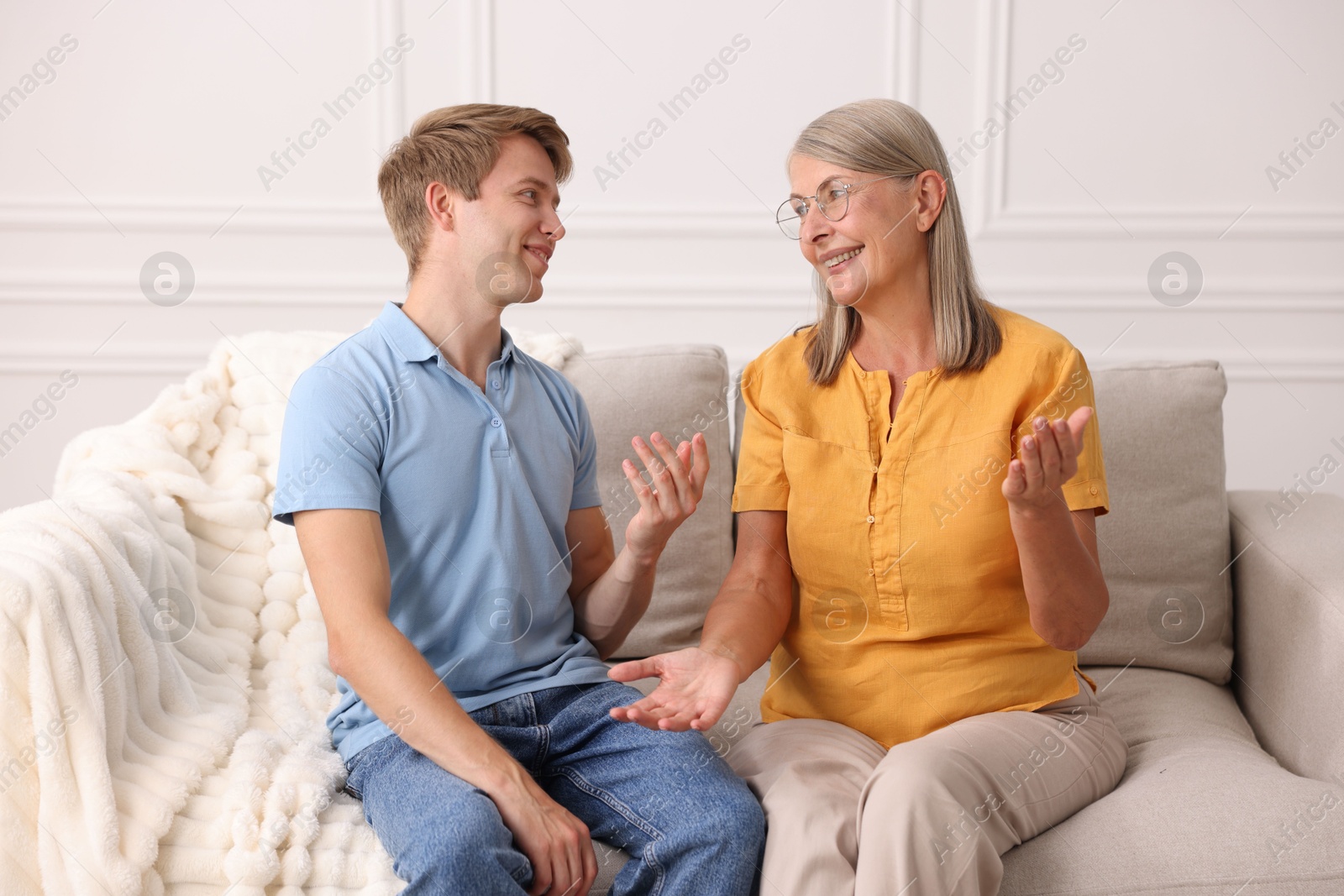 Photo of Happy son and his mother talking on sofa at home