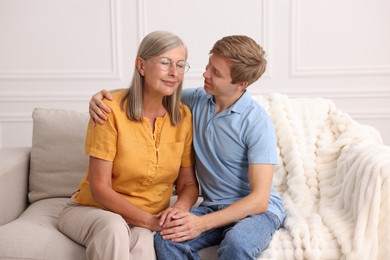 Photo of Son and his mother on sofa at home. Family bonding