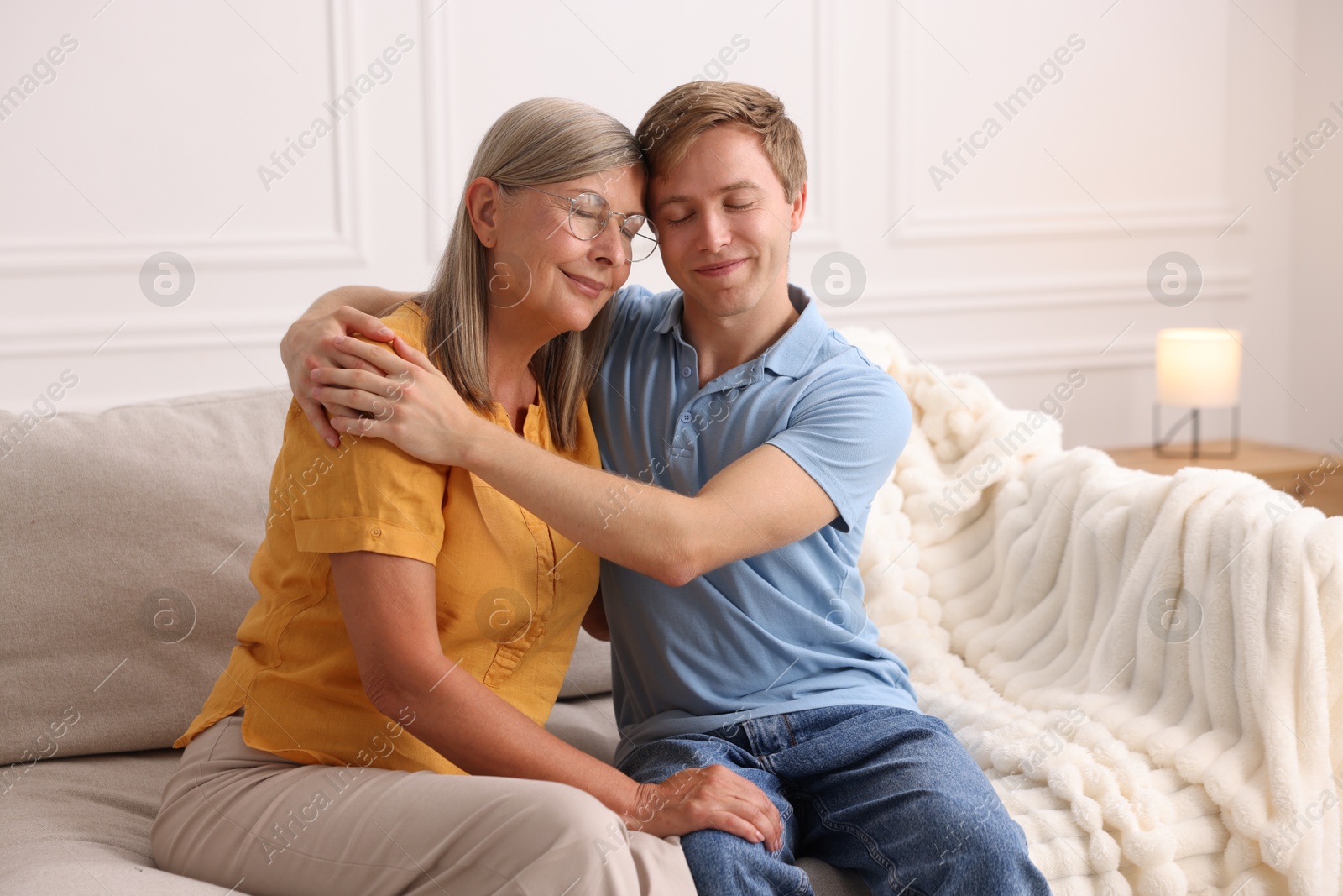 Photo of Son hugging his mother on sofa at home