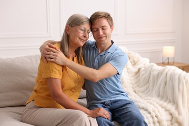 Photo of Son hugging his mother on sofa at home